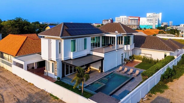 A modern two-story house with a swimming pool, solar panels, and a view of the city skyline. - Luxury 4 Bedroom Pool Villa - PV8 (Hua Hin)