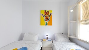 A hotel room with two beds, a nightstand, a lamp, and a painting of a giraffe on the wall. - Apartment Parra by Interhome (Nerja)