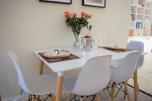 Una mesa de comedor preparada con platos, cubiertos y un jarrón de flores.