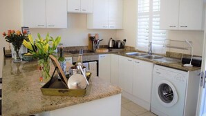 Una cocina moderna con armarios blancos, lavavajillas integrado y encimera de granito.