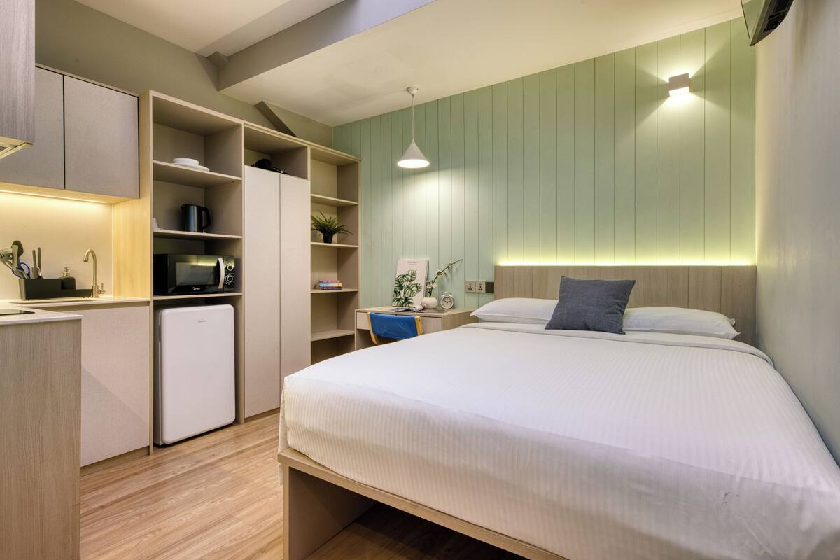 A modern bedroom with a bed, a desk, and built-in storage.