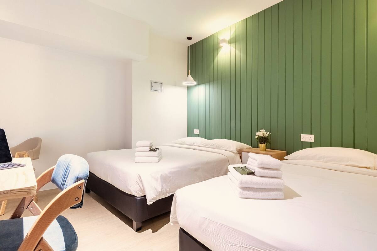 A hotel room with two beds, a desk, and a chair.