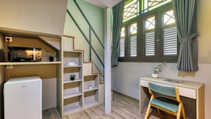 Une pièce de taille modeste, équipée d’un bureau, d’une chaise et d’un petit réfrigérateur.