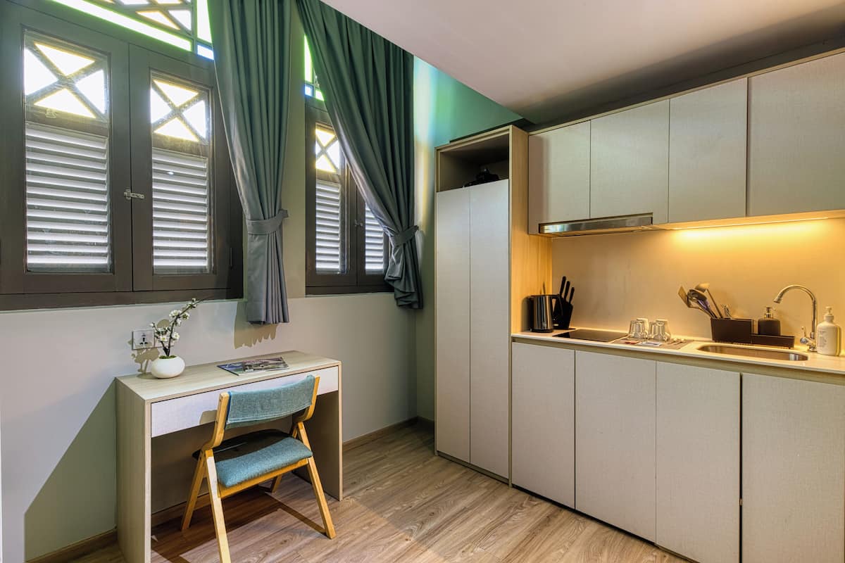 A compact kitchen with a wooden desk, a chair, and a built-in cabinet.