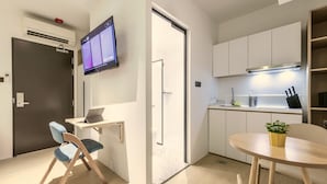 Une cuisine moderne équipée d’un téléviseur à écran plat, d’un coin repas avec une table et des chaises, et d’un petit coin salon avec un fauteuil.