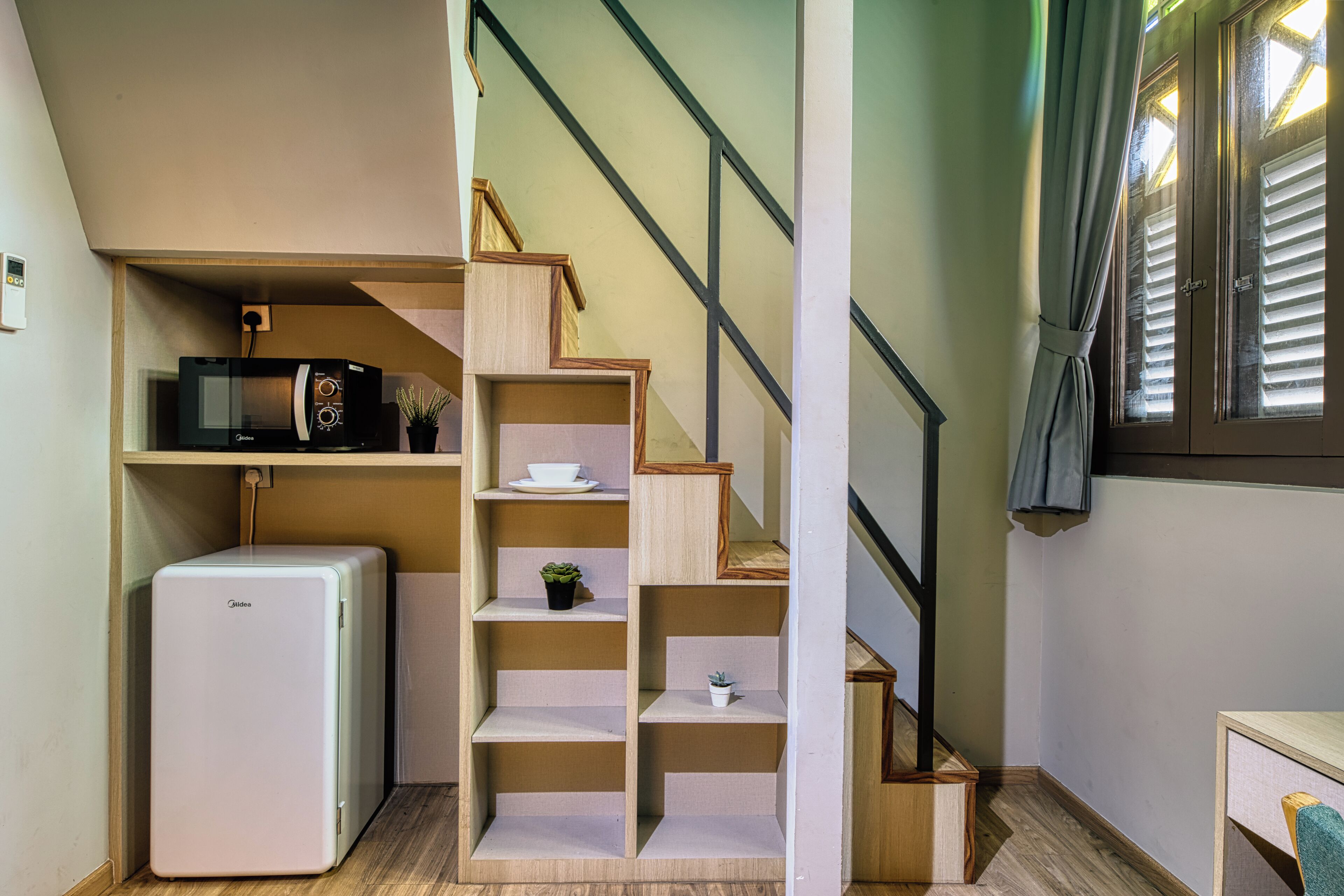 Una cocina compacta con microondas, un refrigerador pequeño y estantes de madera.