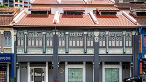 Un bâtiment à deux étages, doté d’un toit traditionnel recouvert de tuiles, d’un balcon orné de balustrades décoratives et d’une devanture avec une enseigne.