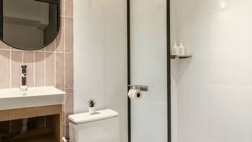 Un baño moderno con lavamanos, inodoro y ducha.