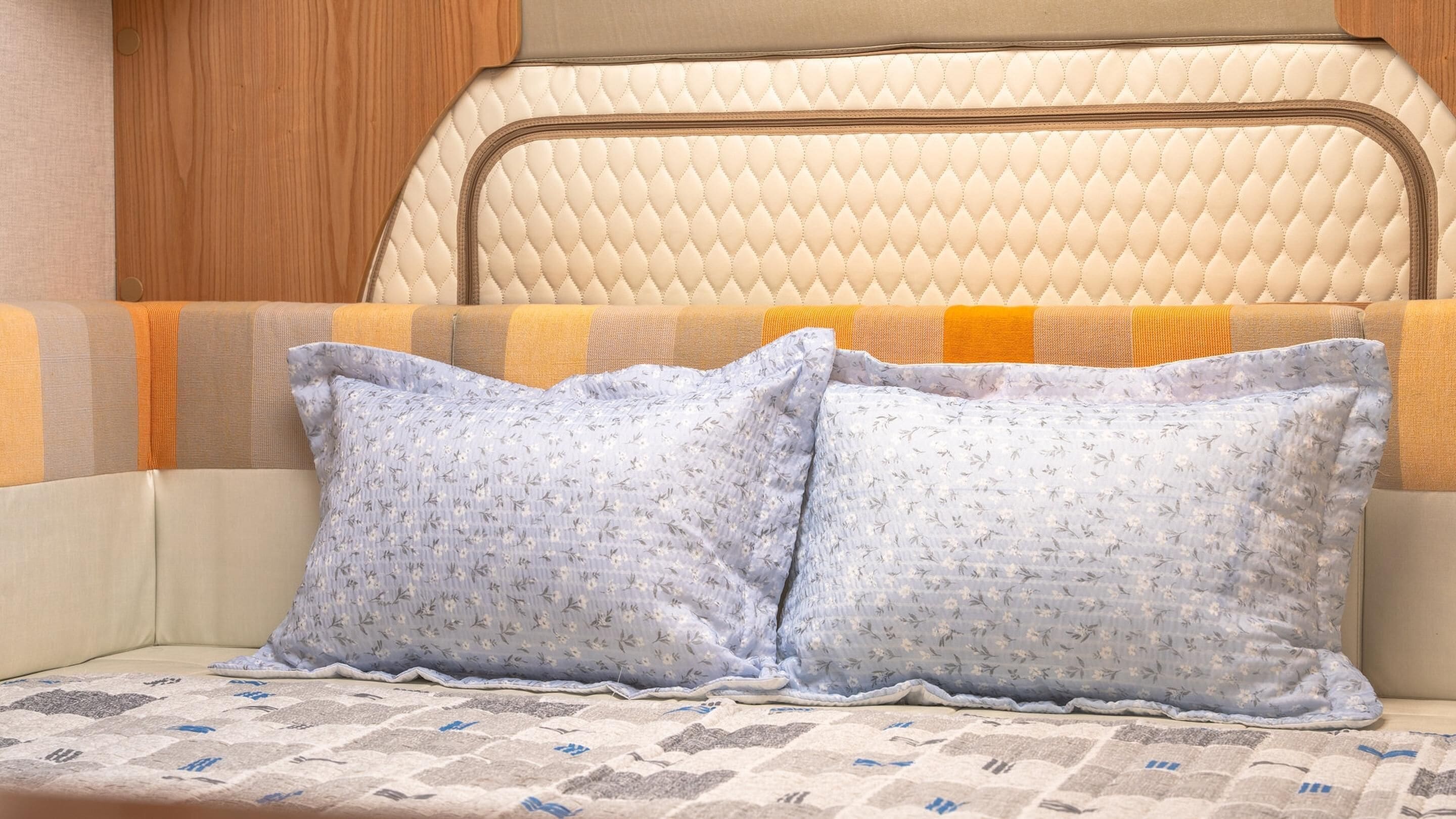 A cozy interior with a cushioned bench, two pillows, and a patterned blanket.