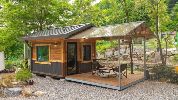 A small cabin with a wooden exterior, a glass door, and a patio with outdoor furniture.