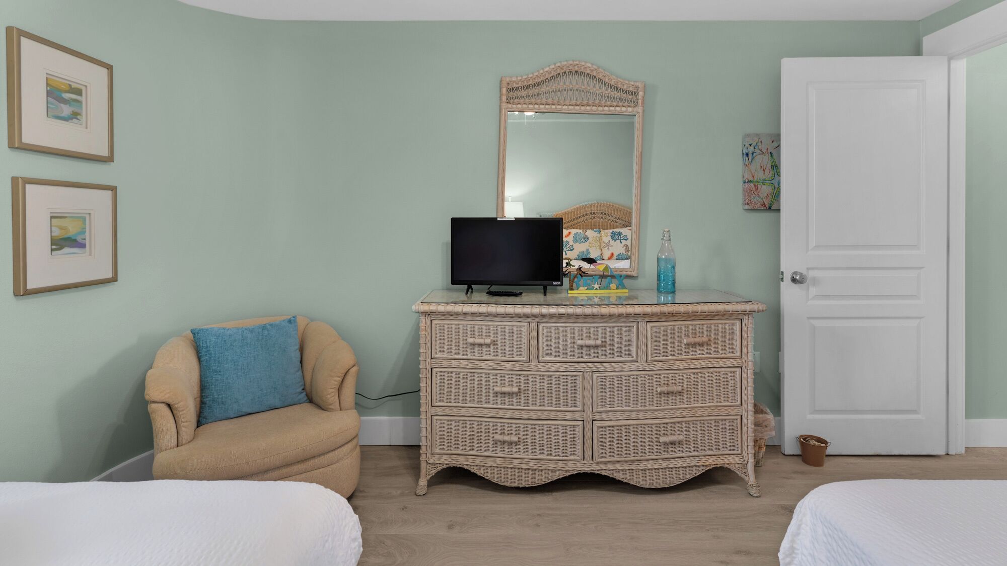 Een slaapkamer met een bed, een dressoir met spiegel en een televisie.