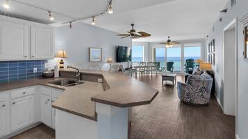 A modern kitchen with a large island, white cabinetry, and a view of the ocean.