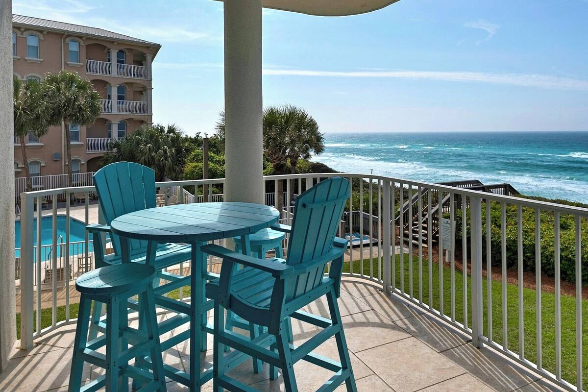 A balcony with a view of the ocean, featuring a table and chairs.