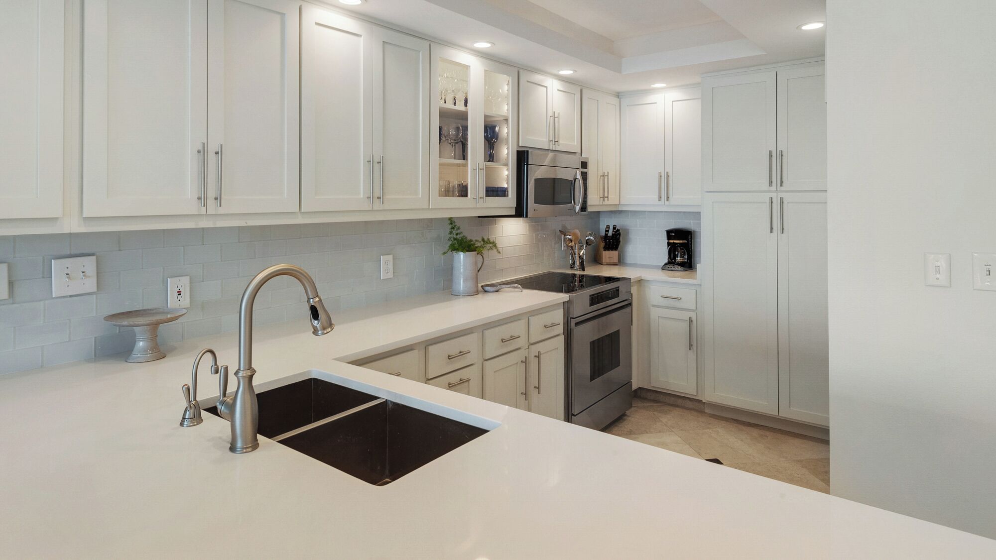 A modern kitchen with white cabinetry, stainless steel appliances, and a central island with a sink.