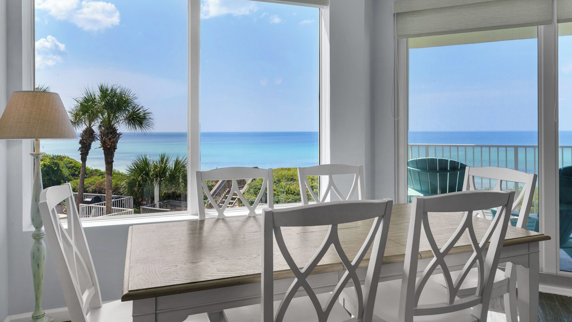 A balcony with a table and chairs overlooking a coastal view.