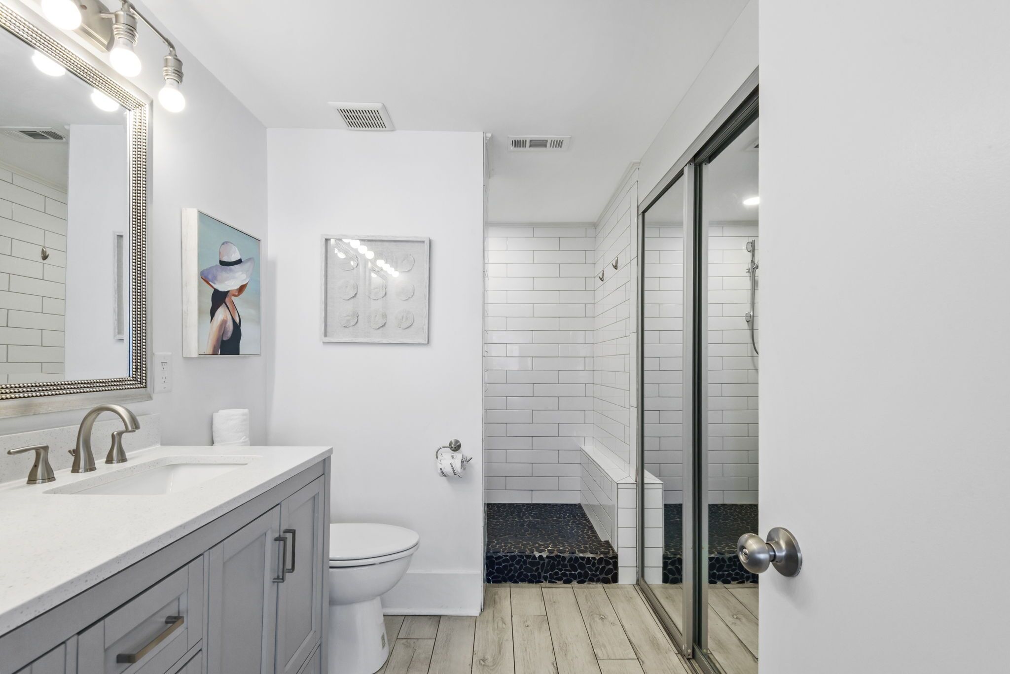 A modern bathroom with a white vanity, a toilet, a shower with a glass door, and a tiled floor.