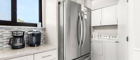 Una cocina con un refrigerador de acero inoxidable, una cafetera, un tostador y una lavadora.