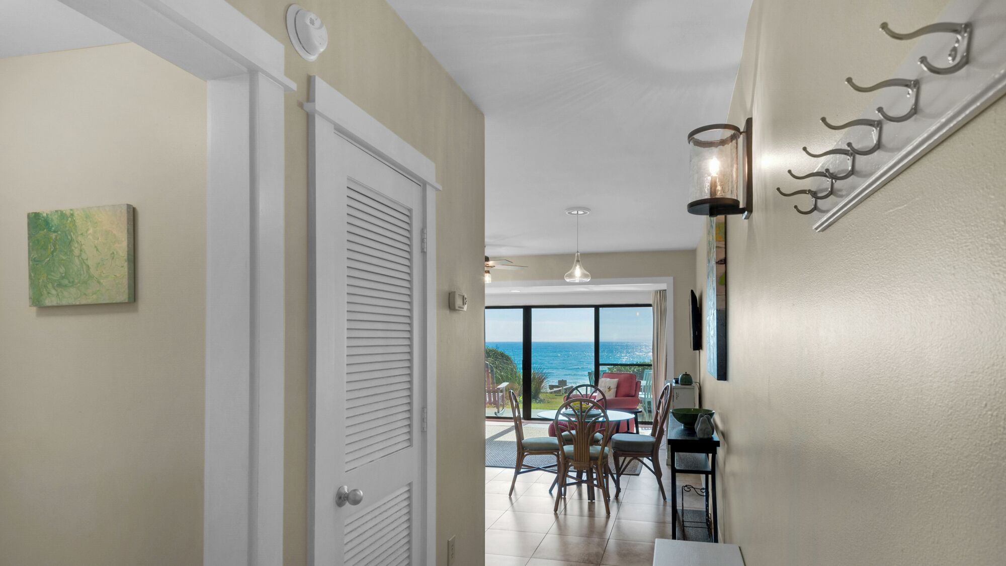 A hallway leading to a dining area with a view of the ocean.