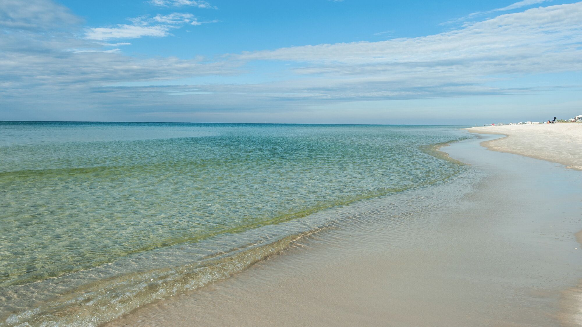 Ein Strand mit klarem, seichten Wasser und einem Sandufer.