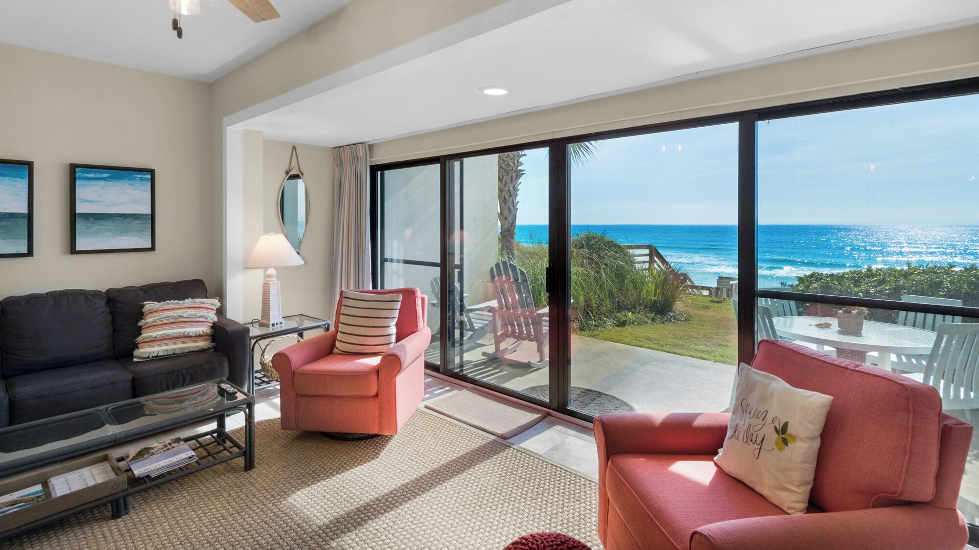 A spacious living room with a large sliding glass door leading to a balcony overlooking the ocean.