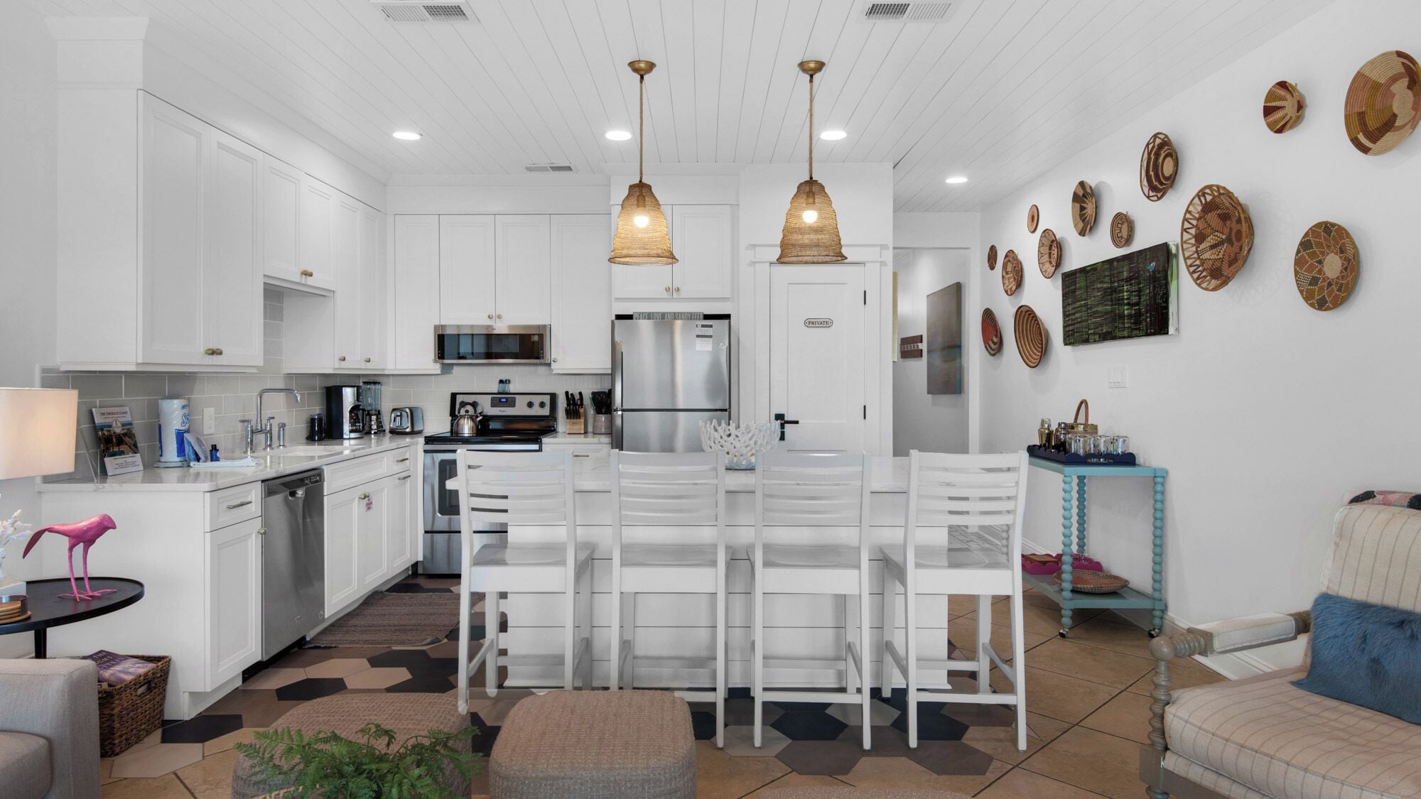 A modern kitchen with white cabinetry, stainless steel appliances, and a central island with seating.