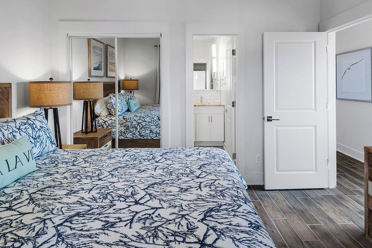 A bedroom with a bed, bedside tables, a dresser, and a door leading to a bathroom.
