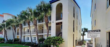 A multi-story residential building with balconies and a private access gate.