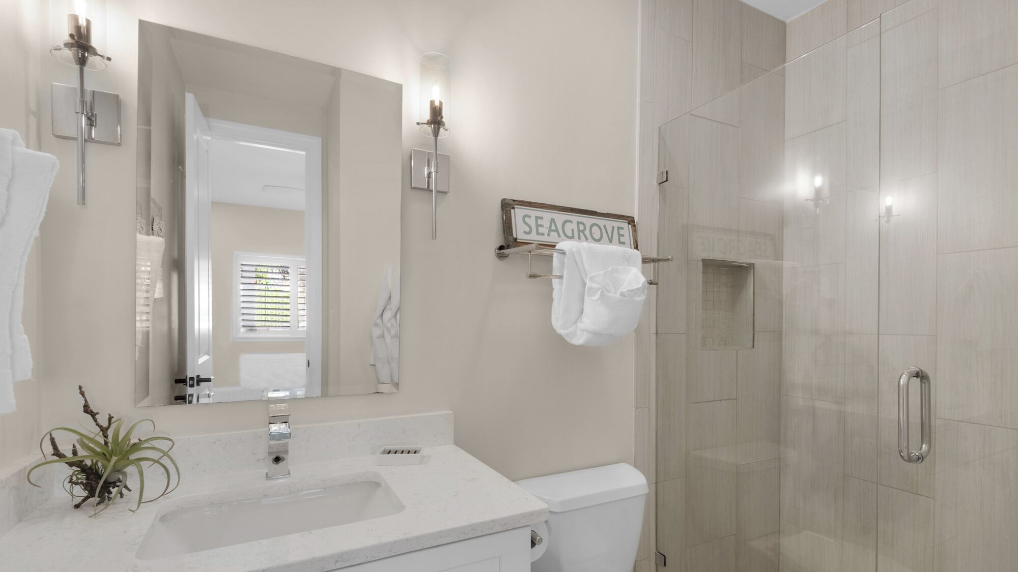 Un baño moderno con lavamanos blanco, un espejo, inodoro y cabina de ducha.