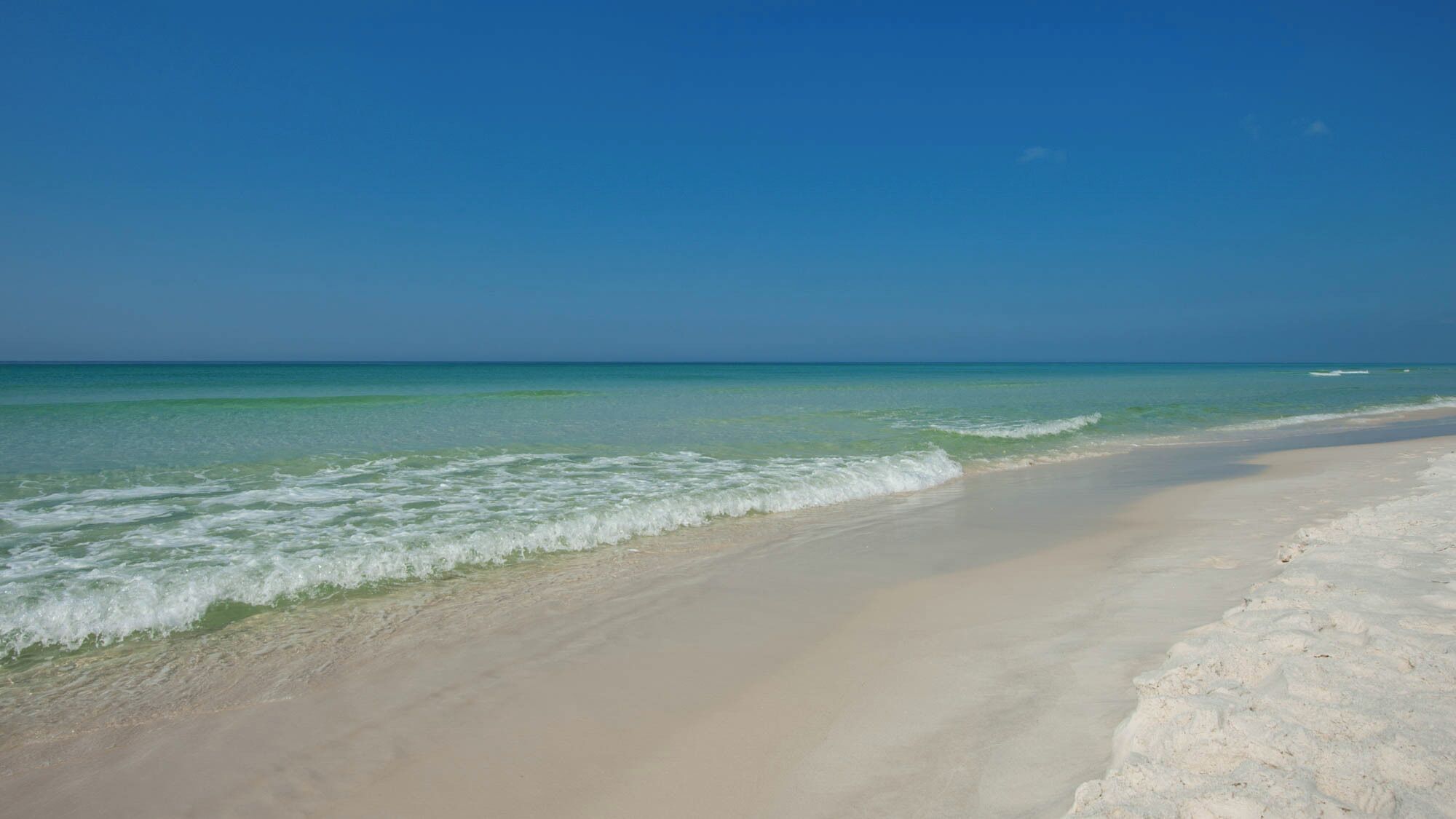 A beach with clear turquoise water and a sandy shore.