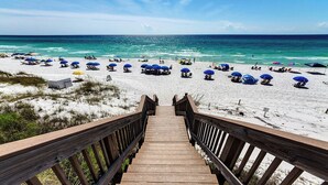 A wooden staircase leading to a beach with white sand and blue umbrellas. -  Palms at Seagrove (Santa Rosa Beach)