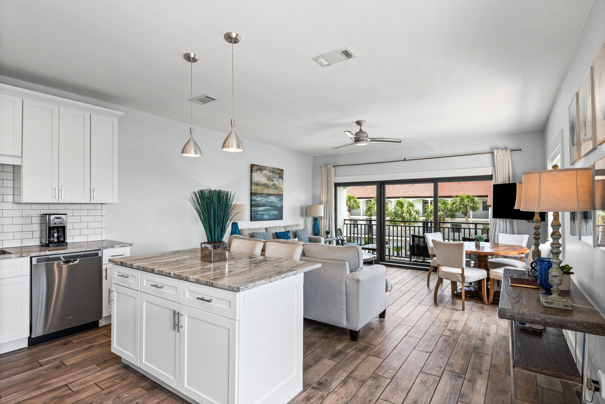 Una cocina moderna con armarios blancos, una isla central y un comedor con mesa y sillas.