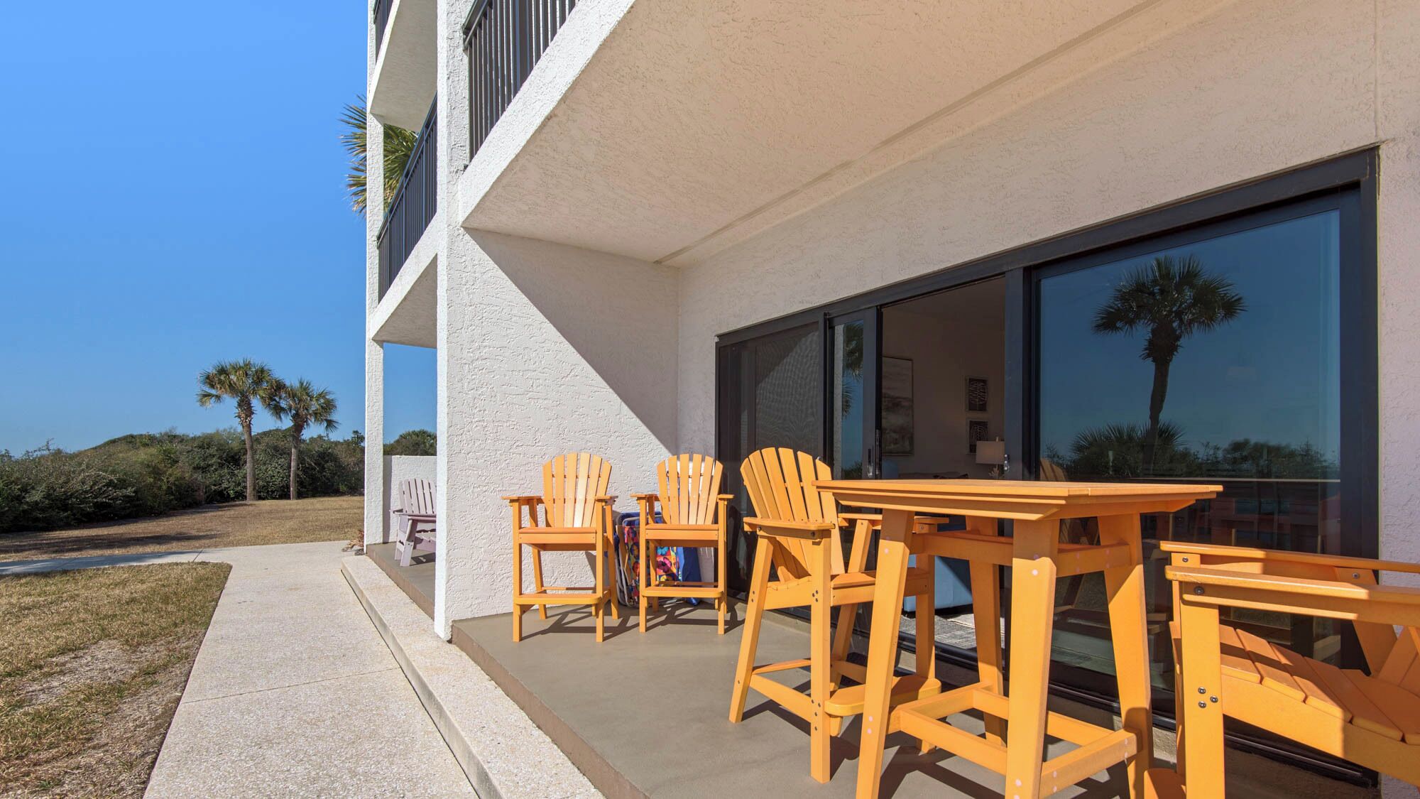 A modern building with a patio area featuring wooden chairs and tables.
