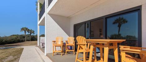 A modern building with a patio area featuring wooden chairs and tables.