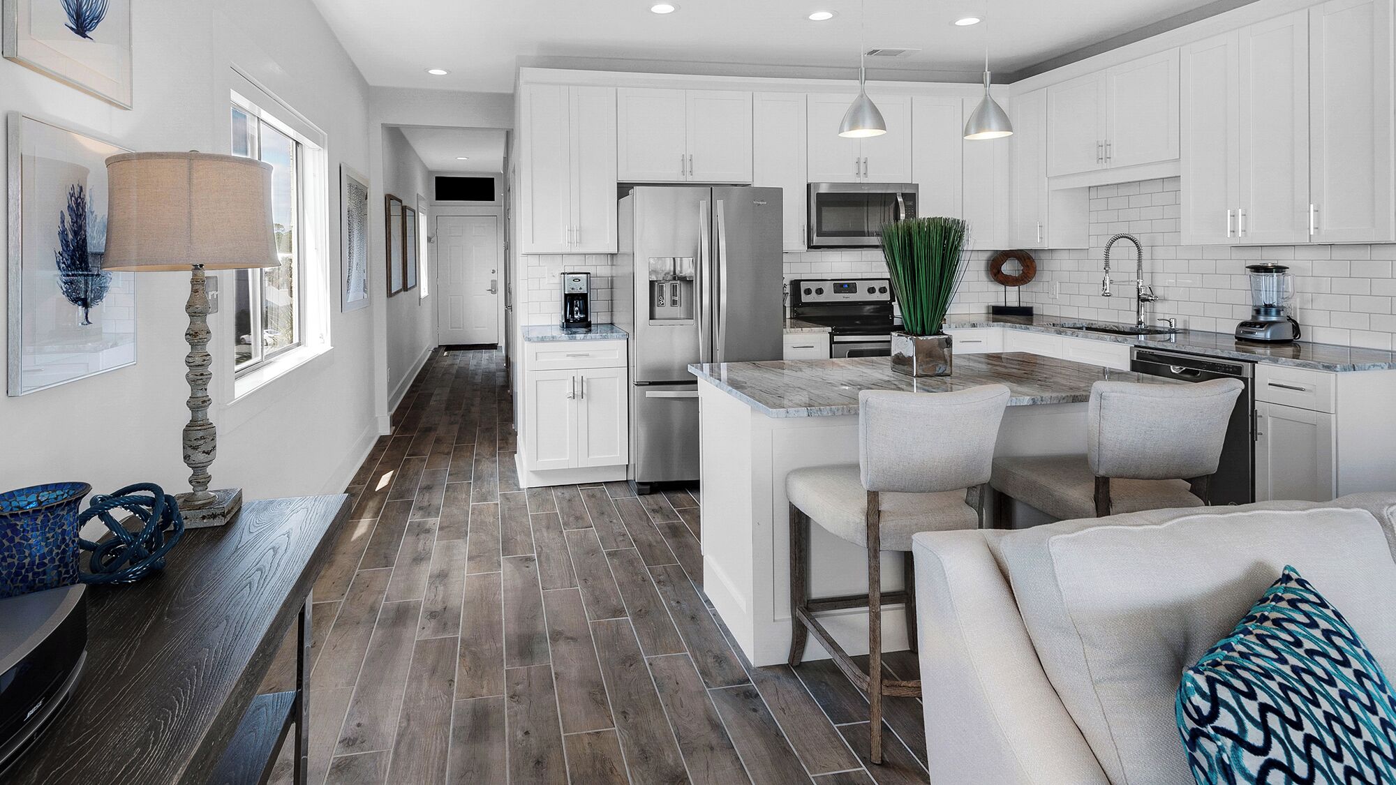 A modern kitchen with white cabinets, stainless steel appliances, and a central island with bar stools.