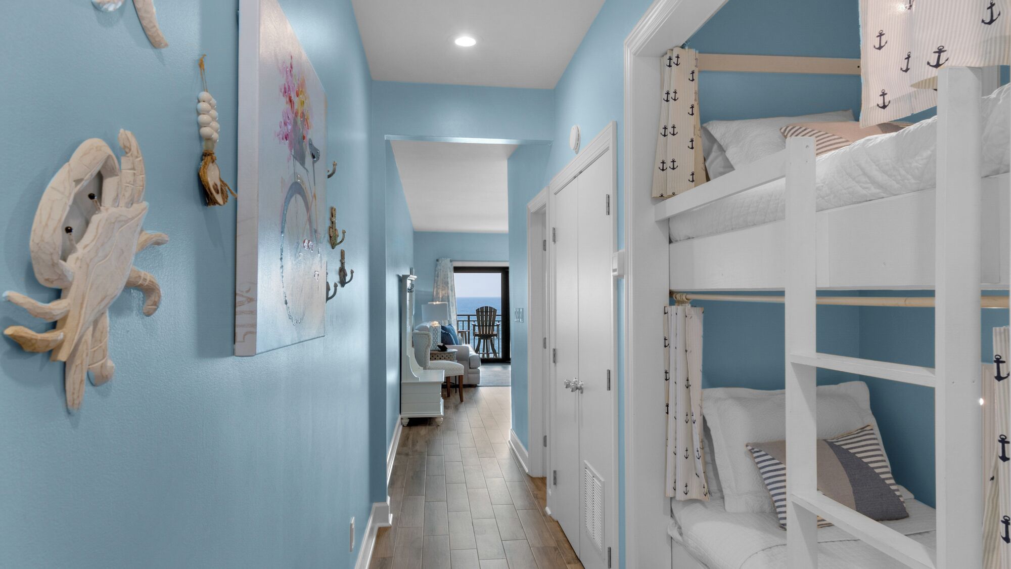 A room with a bunk bed, nautical-themed decor, and a view to the outside.