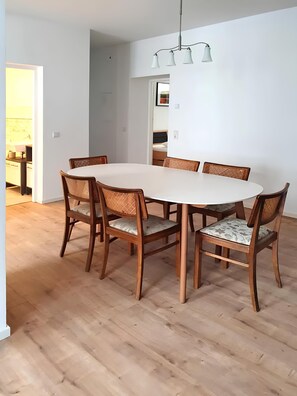 A dining area with a round table, six wooden chairs with woven seats, and a pendant light fixture. - Apartment 'Geräumige Moderne 3 Raumwohnung' with Shared Terrace and Wi-Fi (Dohna)