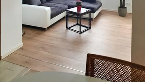A modern living room with a sectional sofa, a small table with a potted plant, a window with blinds, and a red pendant light. - Apartment 'Geräumige Moderne 3 Raumwohnung' with Shared Terrace and Wi-Fi (Dohna)