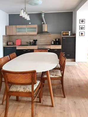 A modern kitchen with a round dining table, wooden chairs, and a built-in oven.