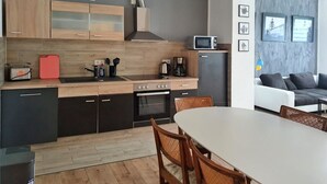 A modern kitchen with wooden cabinets, a microwave, and a dining area with a white table and wicker chairs. - Apartment 'Geräumige Moderne 3 Raumwohnung' with Shared Terrace and Wi-Fi (Dohna)