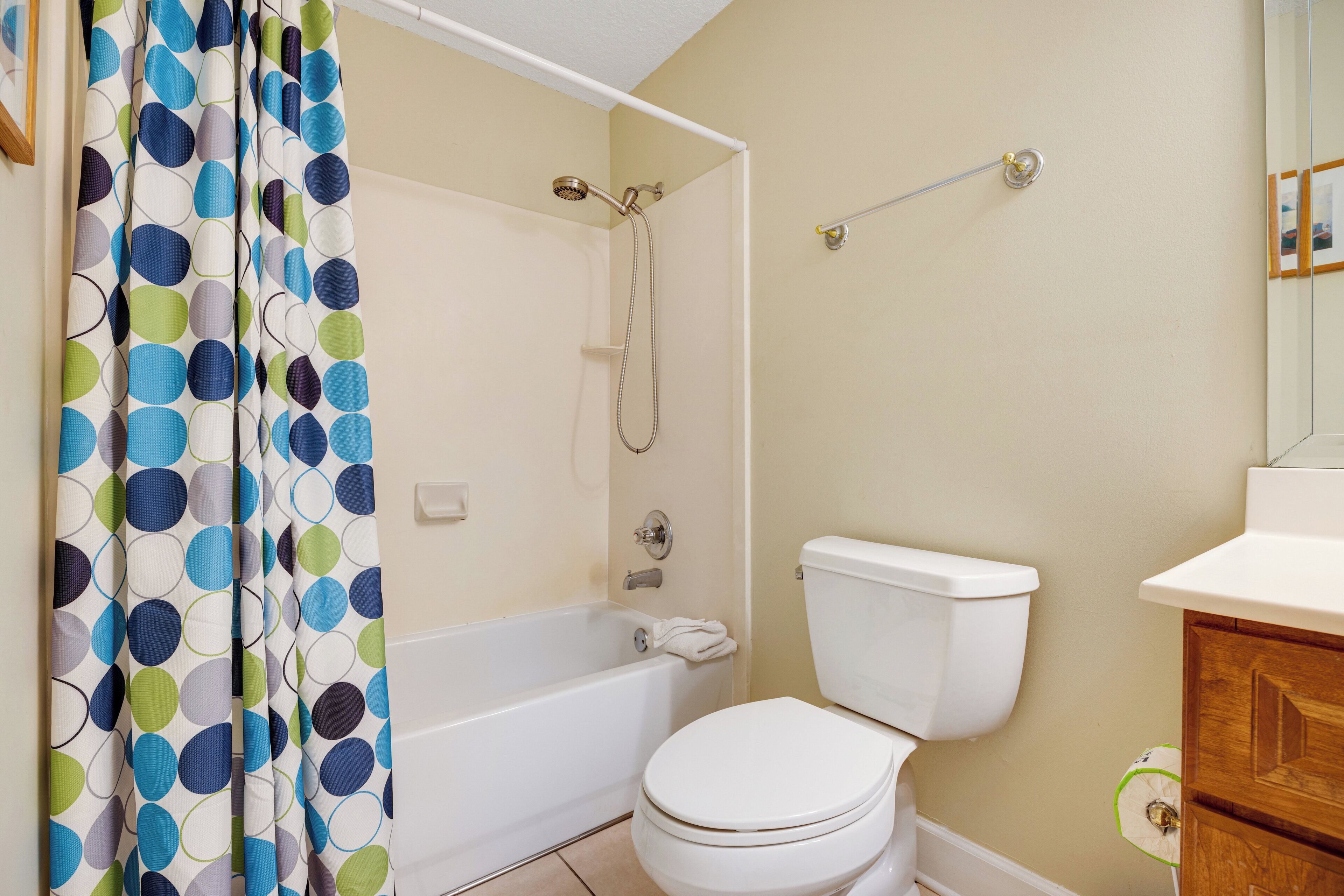 A bathroom with a bathtub, toilet, and a shower curtain with a polka dot pattern.