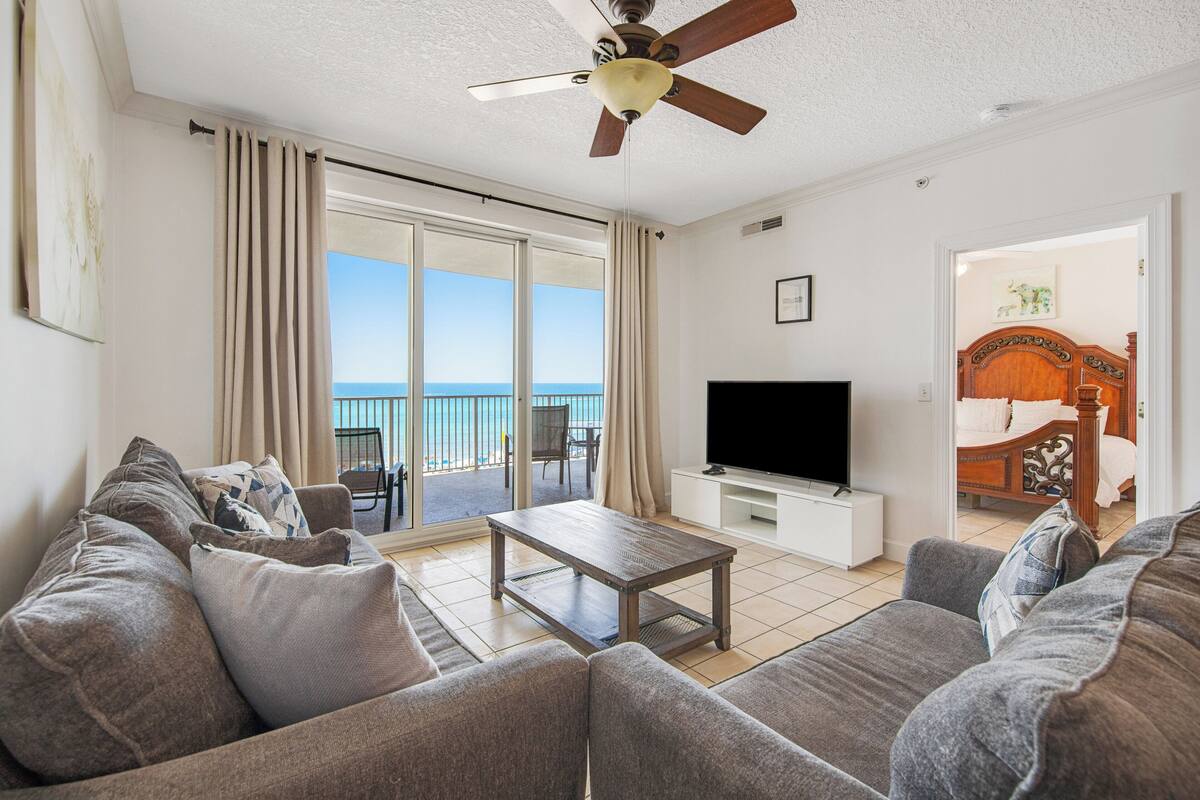 Un salon comprenant un canapé, une table basse, un téléviseur et un balcon avec vue sur la mer.