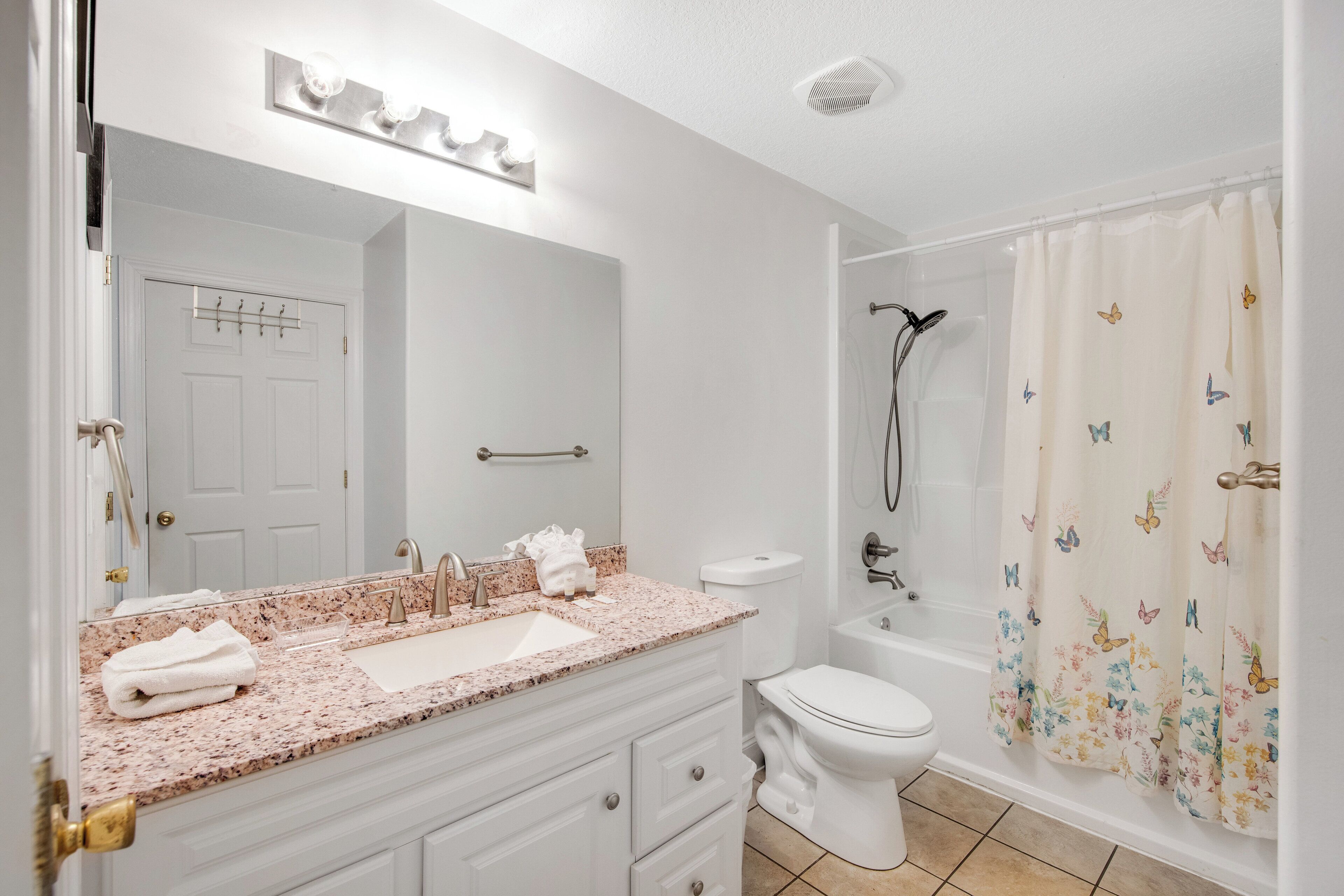 A bathroom with a sink, mirror, toilet, and shower.