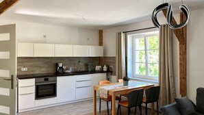 Una cocina moderna con armarios blancos, encimera de madera y horno empotrado.