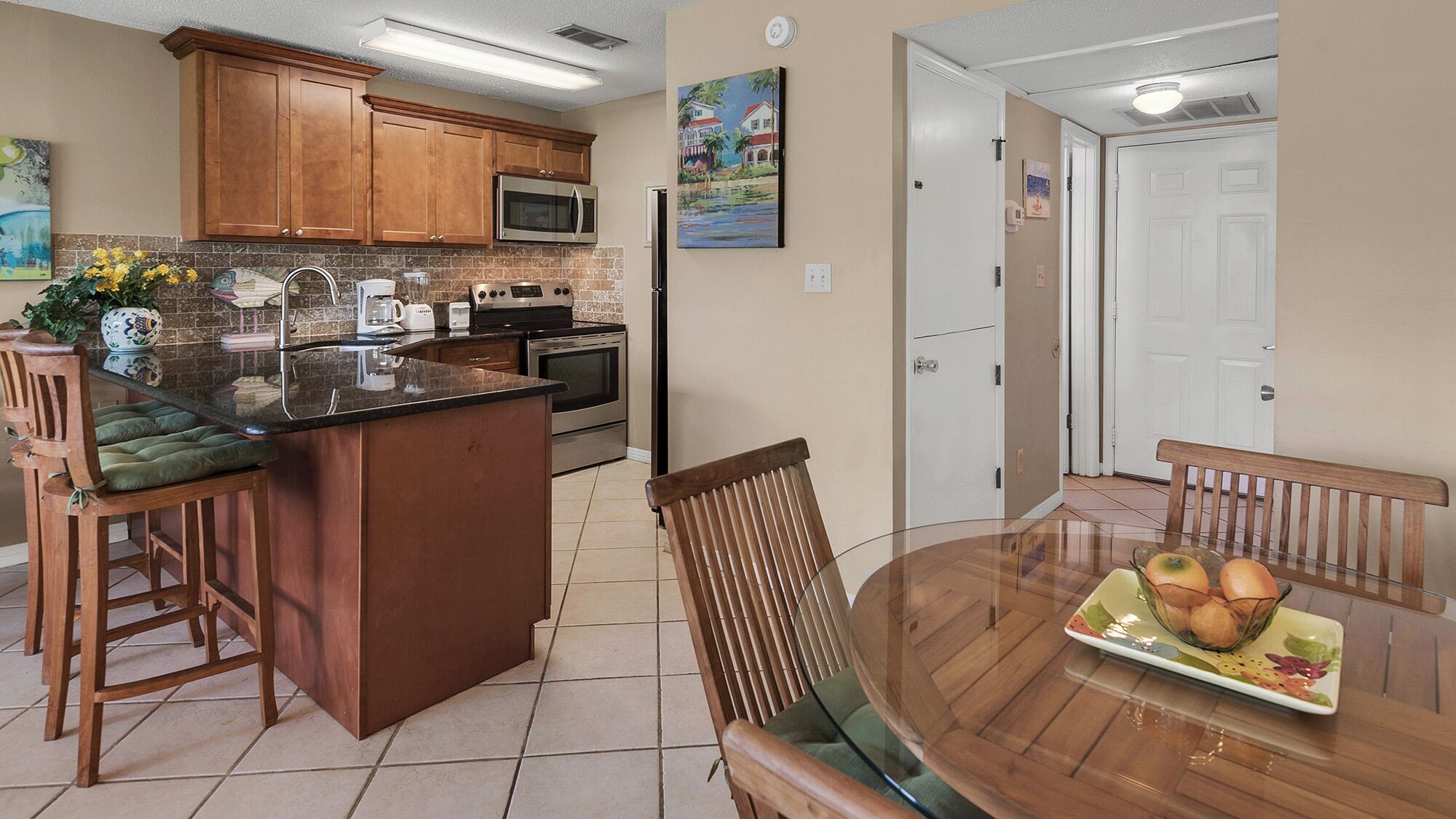 A kitchen with wooden cabinets, a microwave, a stove, and a dining area with a table and chairs.