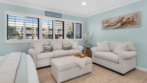 A living room with a sofa set, a coffee table, and a painting on the wall. - Hidden Beach Villas (Santa Rosa Beach)