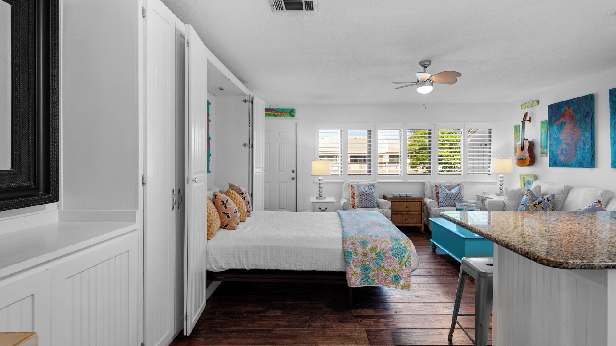 A bedroom with a bed, a desk, and a window with blinds.