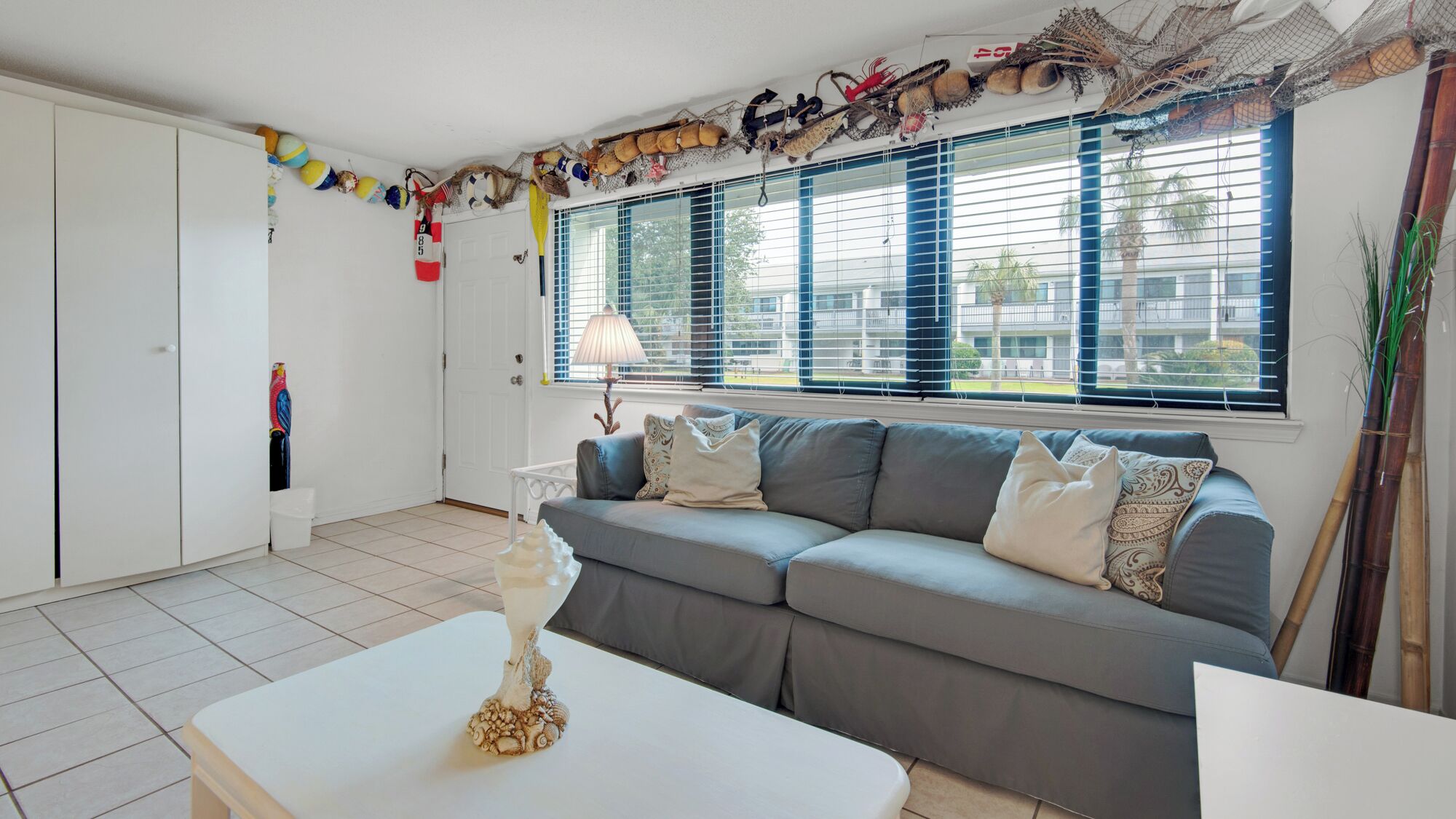 A living room with a grey sofa, white coffee table, and a decorative shell centerpiece.