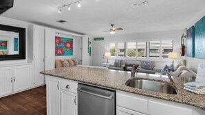 A modern kitchen with granite countertops, a stainless steel sink, and white cabinetry. - Hidden Beach Villas (Santa Rosa Beach)