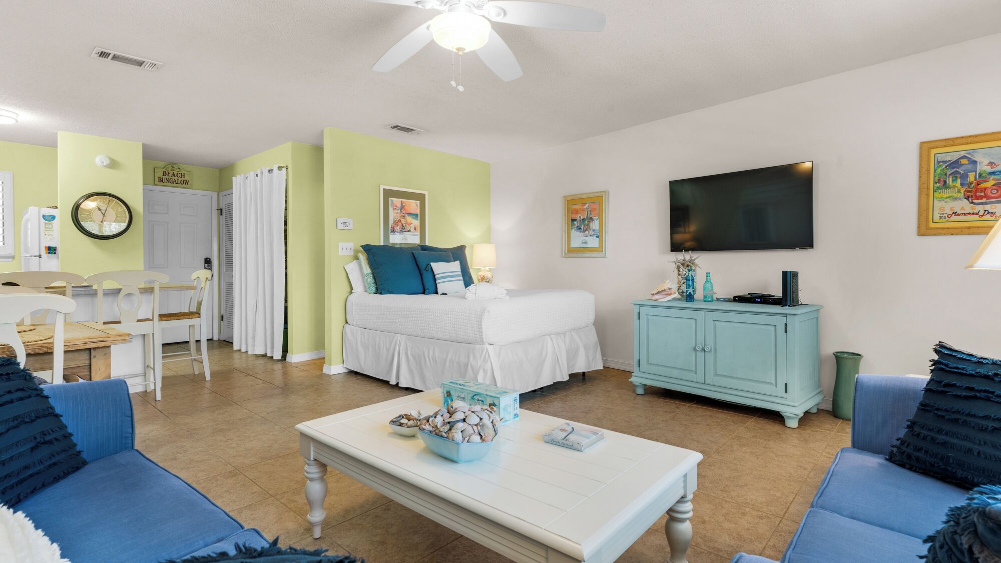 A room with a bed, a TV, a dining area, and a kitchenette.