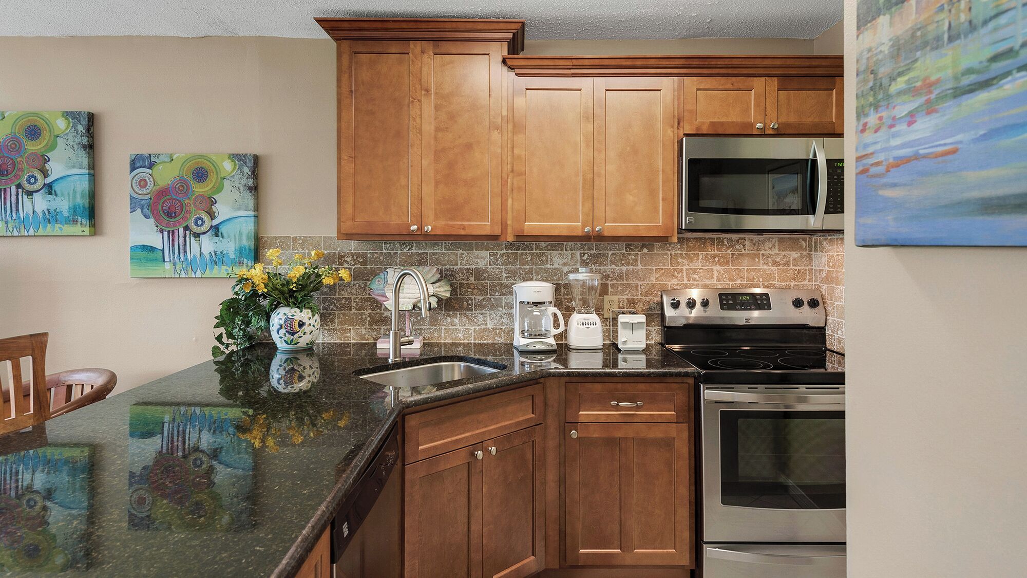 A kitchen with wooden cabinets, a stainless steel refrigerator, a microwave, a stove, and a coffee maker.